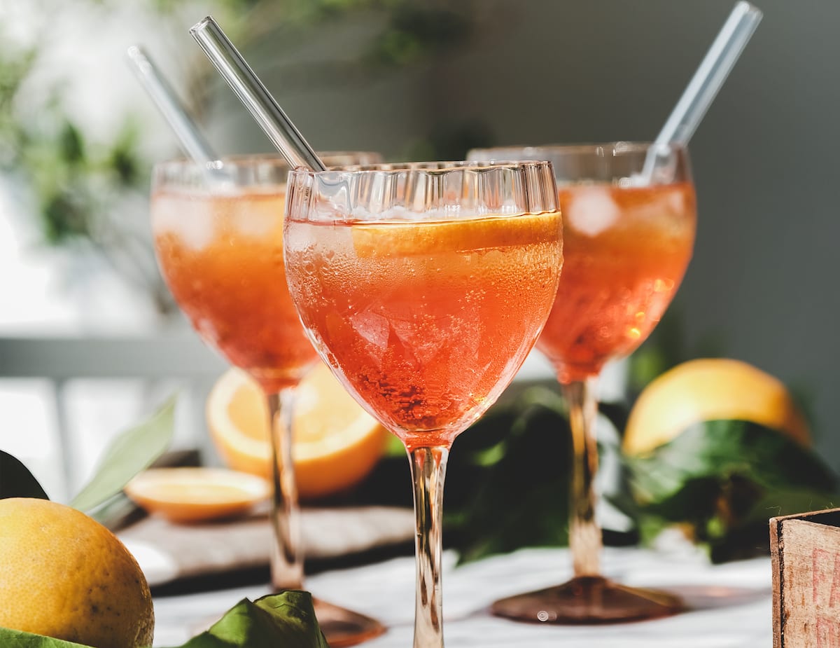 Die besten Sour Cocktails - Von der Herkunft bis zum Rezept 7 Aperol sour aperitif alkoholisches kaltgetränk in gläsern mit orangen und eis über grauer marmortafel, selektiver fokus. Konzept sommer-erfrischungsgetränk